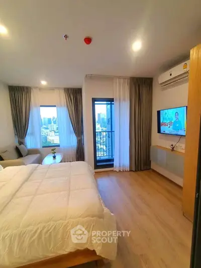 Modern bedroom with city view, cozy bed, and wall-mounted TV in a stylish apartment.