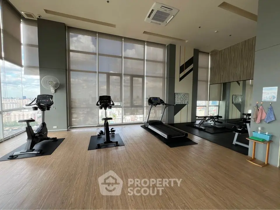 Spacious gym with modern equipment and city view in luxury apartment complex