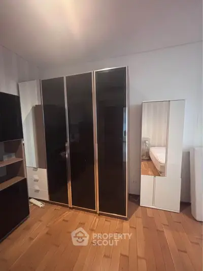 Spacious bedroom with sleek wardrobe and wooden flooring