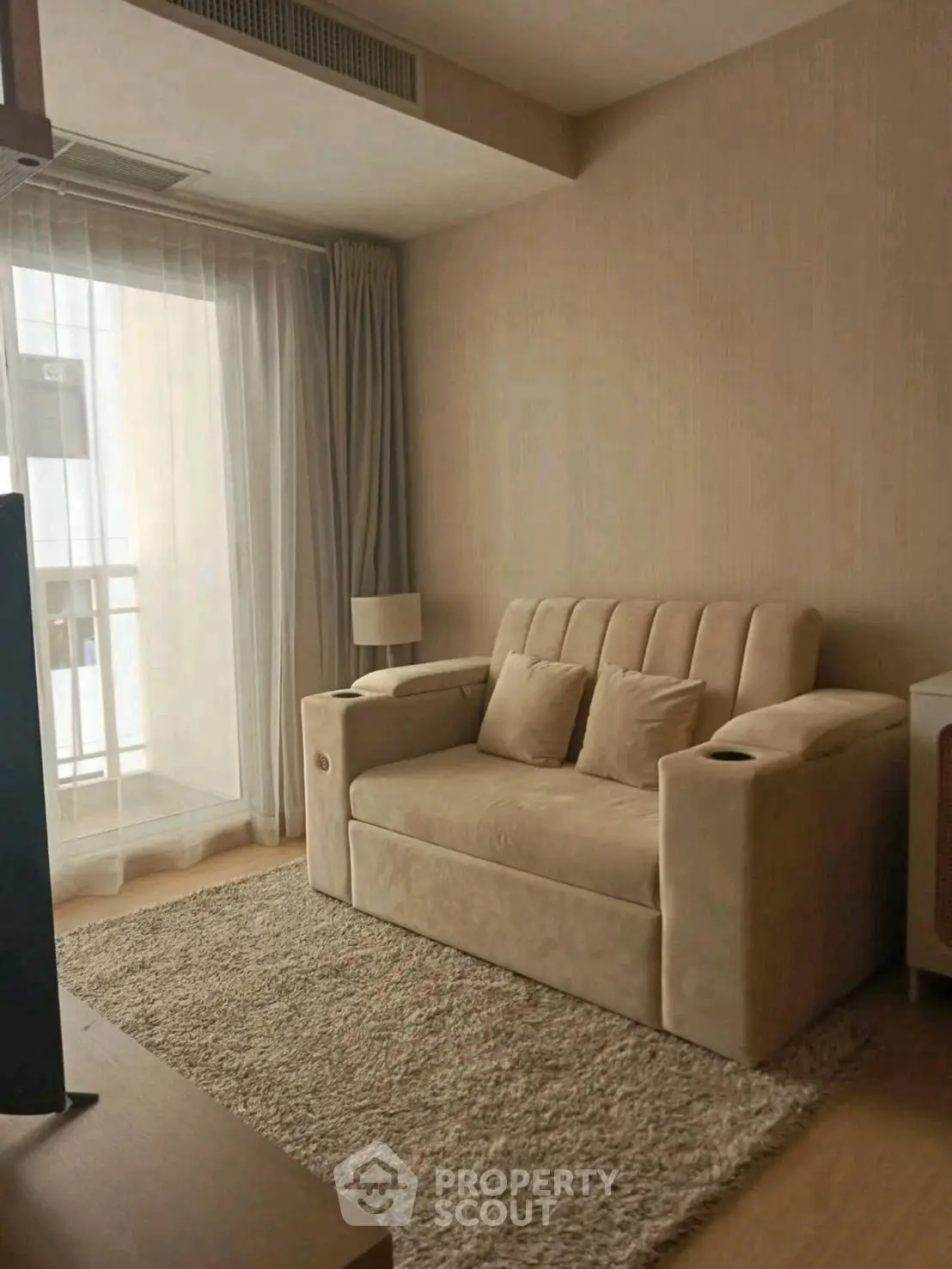 Cozy living room with plush beige sofa and soft rug, perfect for relaxation.