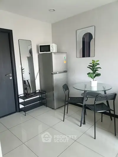 Modern kitchen with sleek fridge, microwave, and stylish dining set in a compact space.