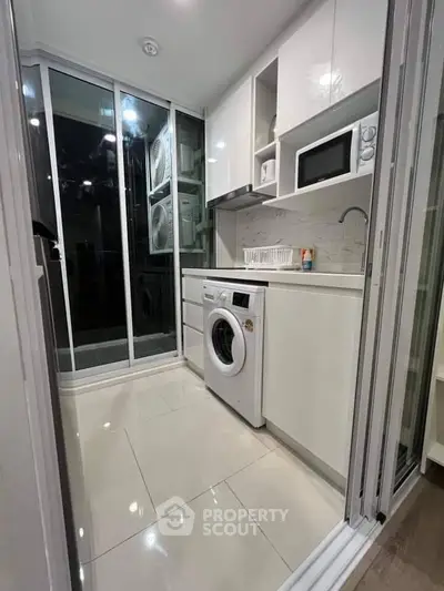Modern compact kitchen with washing machine and microwave in sleek white design.