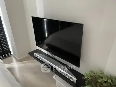 Modern living room with sleek TV setup and soundbar on a stylish stand, perfect for entertainment.