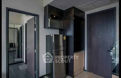 Modern apartment entrance with sleek black cabinetry and stainless steel fridge