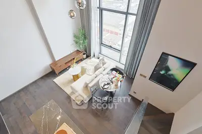 Stunning loft-style living room with high ceilings and large windows offering a panoramic city view.