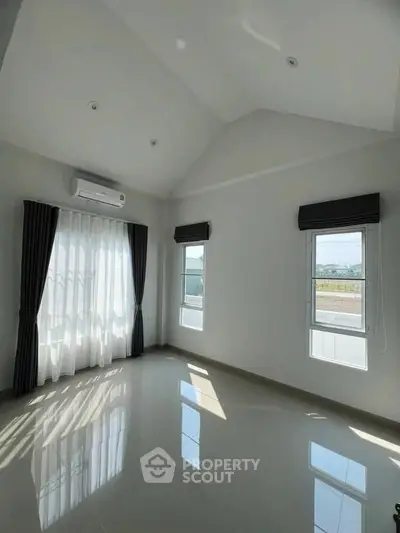 Spacious sunlit room with high ceilings and large windows, perfect for modern living.