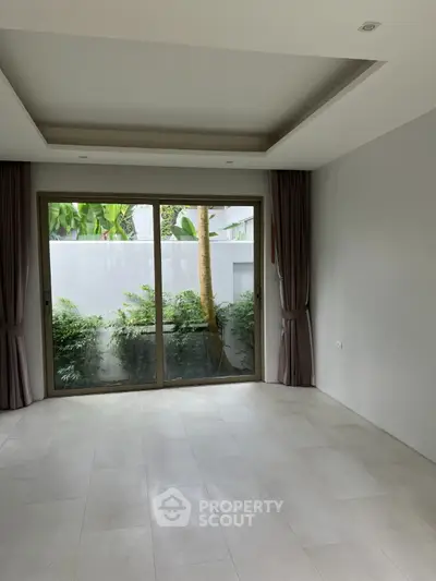 Spacious living room with large window and garden view, perfect for natural light lovers.