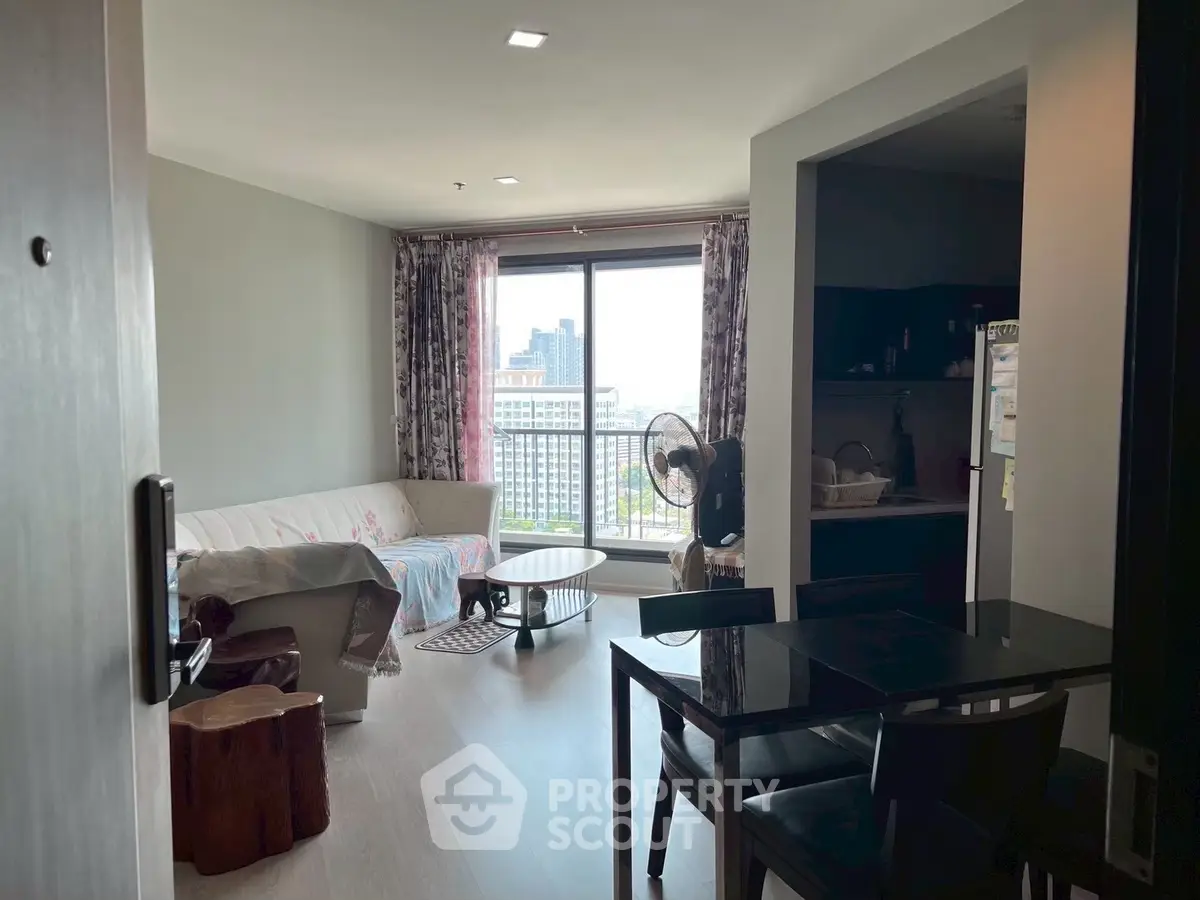 Modern living room with city view, cozy sofa, and dining area in open layout apartment.