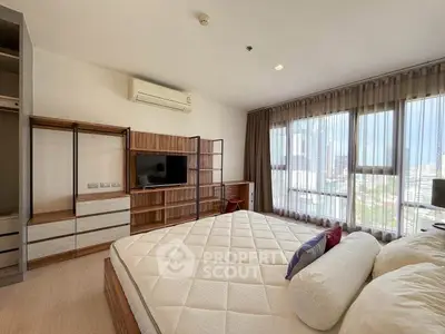 Spacious bedroom with large windows and modern furnishings in a high-rise apartment.