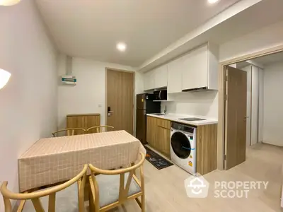 Modern compact kitchen with dining area and washing machine in stylish apartment