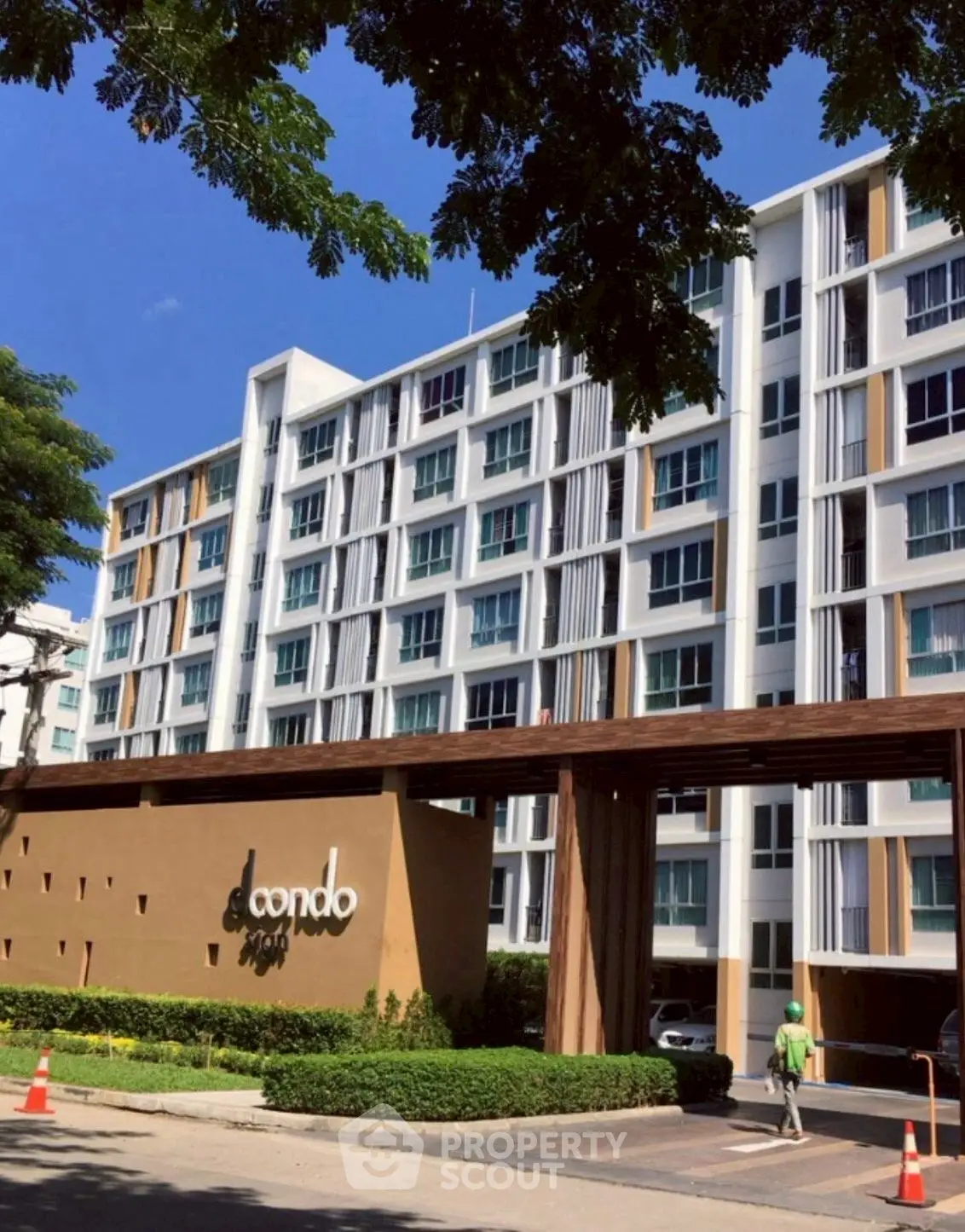 Modern condominium building with stylish facade and lush landscaping in urban setting.