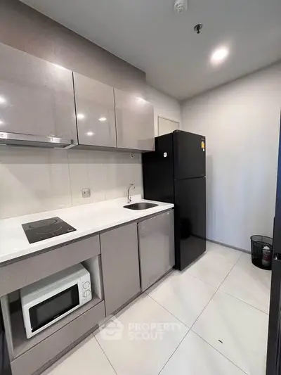 Modern kitchen with sleek cabinetry, induction cooktop, and spacious fridge in a contemporary apartment.