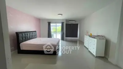 Spacious bedroom with modern furnishings and large window for natural light.