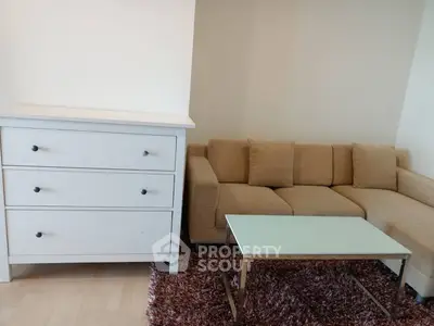Cozy living room with beige sofa, white dresser, and glass coffee table on a plush rug.