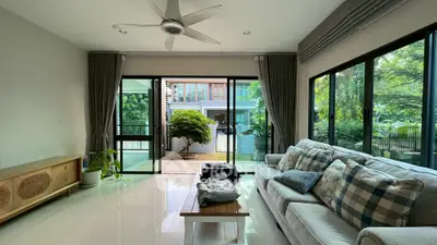 Spacious living room with large windows and garden view, featuring cozy sofa and modern decor.