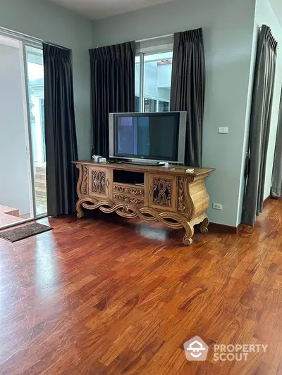 Spacious living room with elegant wooden TV stand and large windows