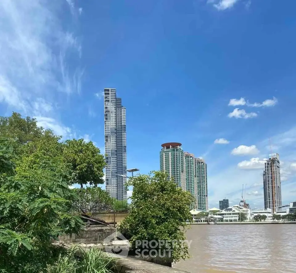 Stunning riverside view of modern skyscrapers against a clear blue sky, perfect for urban living enthusiasts.