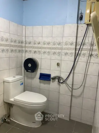 Compact bathroom with shower and toilet in tiled space