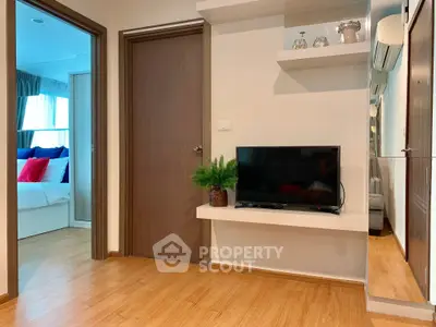 Modern apartment interior with wooden flooring, TV setup, and cozy bedroom view.