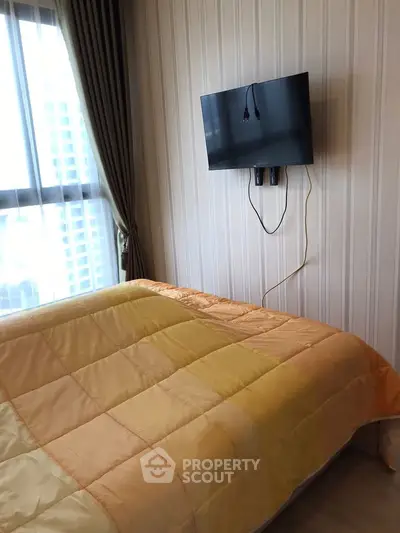 Cozy bedroom with modern wall-mounted TV and large window with city view.