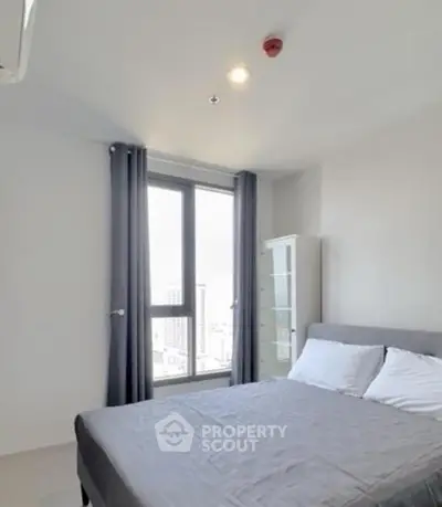 Modern bedroom with large window and city view in a stylish apartment.