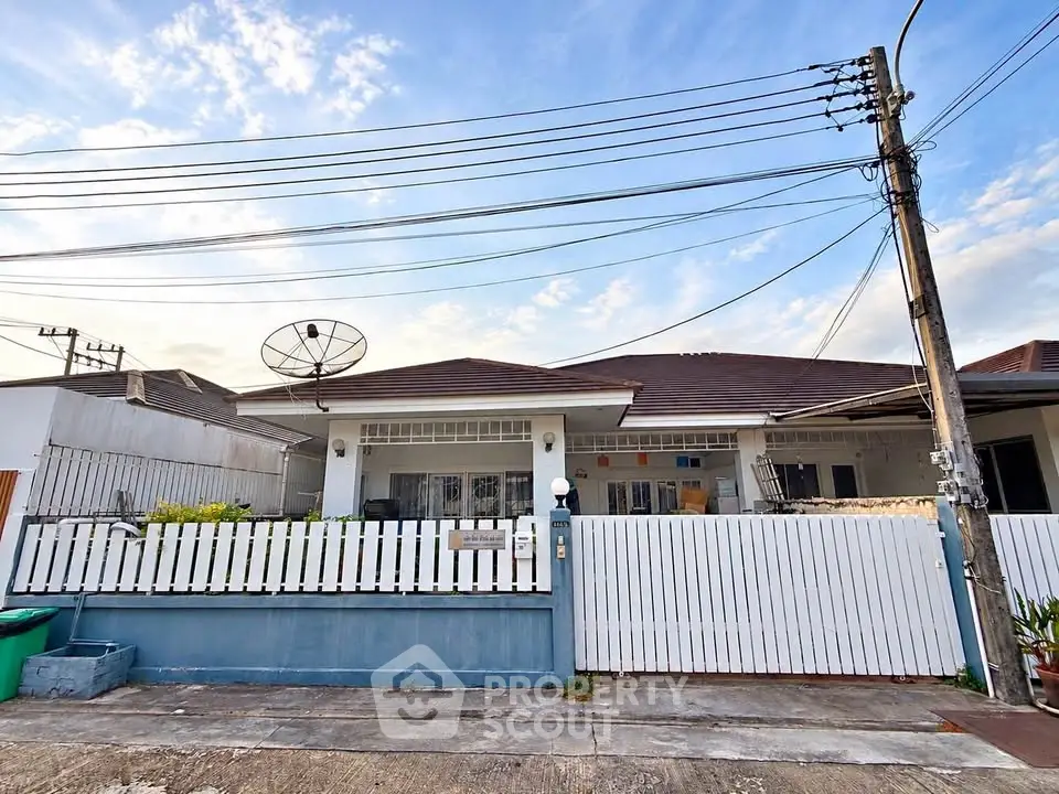 Charming single-story house with white picket fence and satellite dish, perfect for family living.