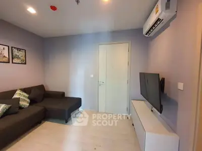 Modern living room with sleek sofa and wall-mounted TV in a cozy apartment.
