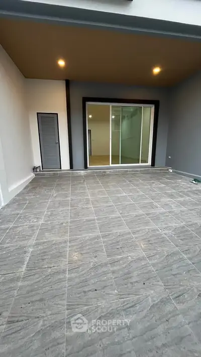 Spacious tiled balcony with sliding glass doors and modern lighting