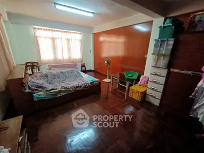 Spacious bedroom with wooden flooring and ample natural light from large window.