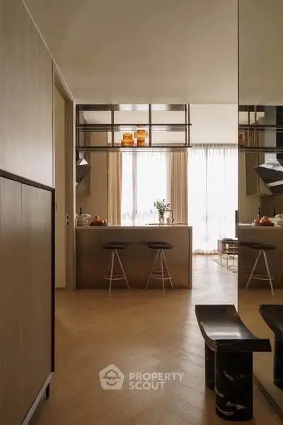 Modern kitchen with sleek design and open layout, featuring stylish bar stools and elegant lighting.