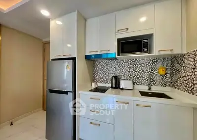 Modern kitchen with sleek appliances and stylish backsplash in a contemporary apartment.