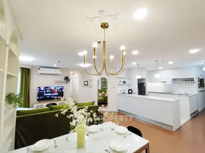 Spacious open-plan living room and kitchen with elegant chandelier and modern decor.
