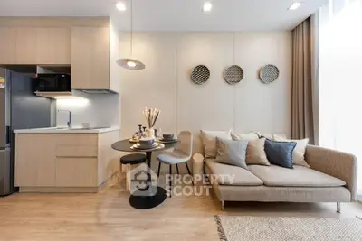 Modern living room with open kitchen, stylish decor, and cozy seating area.