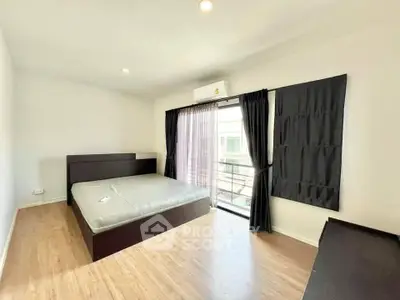 Spacious bedroom with large window and modern furnishings in a bright apartment.