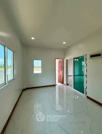 Spacious empty room with glossy marble flooring and large windows for natural light.