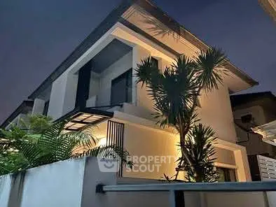 Modern two-story house with sleek design and lush landscaping at dusk.