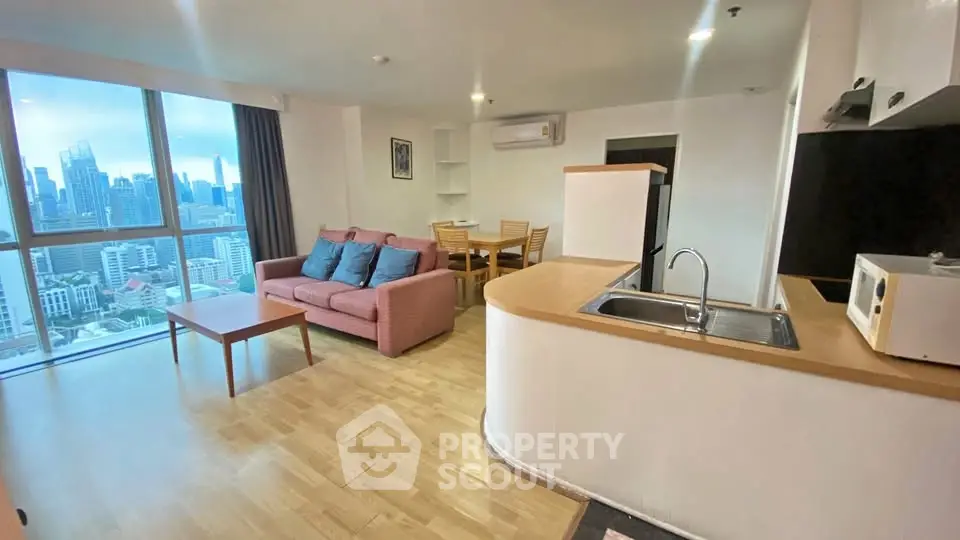 Spacious living room with city view, modern furniture, and open kitchen layout in high-rise apartment.