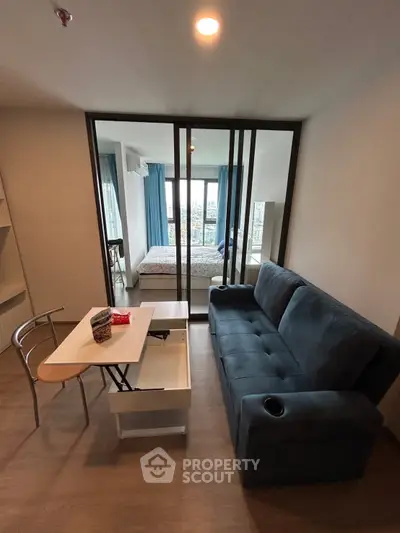 Modern studio apartment with glass partition, cozy living area, and city view from the bedroom.