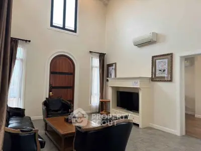 Elegant living room with high ceiling, stylish furniture, and wall-mounted air conditioning.