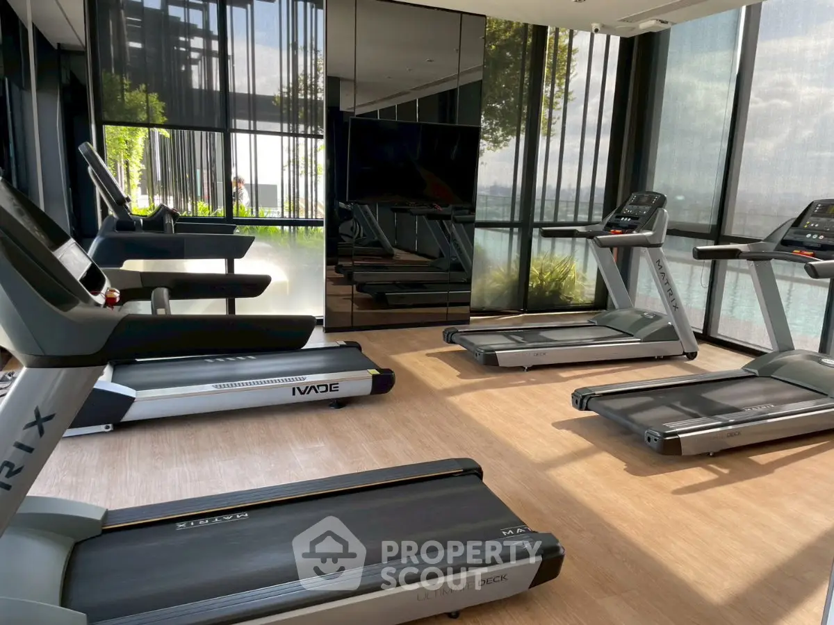 Modern gym with treadmills and large windows offering scenic views.
