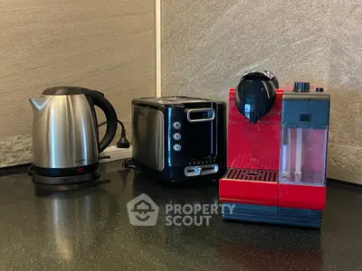 Modern kitchen appliances including a kettle, toaster, and coffee machine on a sleek countertop.