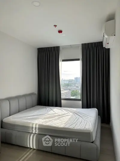 Modern bedroom with large window and city view, featuring a stylish bed and air conditioning.