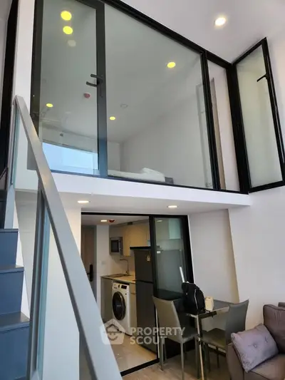 Modern duplex apartment with glass-walled bedroom and compact kitchen