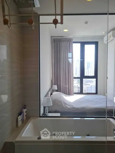 Modern apartment with bathtub and city view from bedroom window.