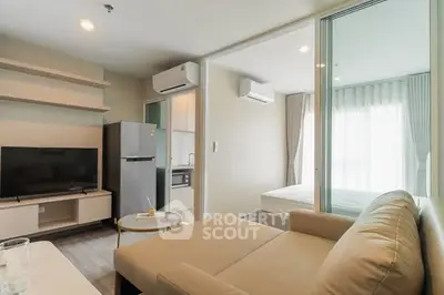 Modern living room with beige sofa, TV, and open kitchen in a stylish apartment.