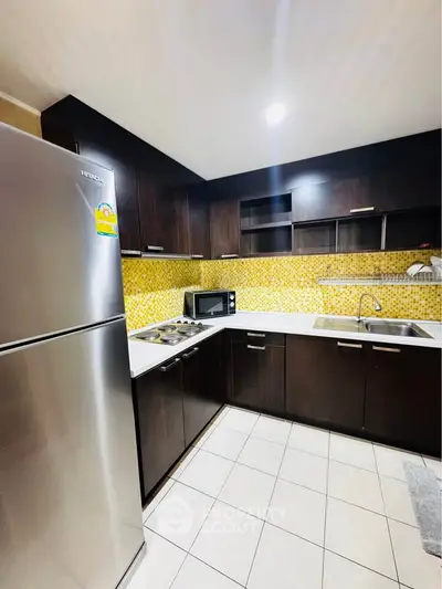Modern kitchen with dark wood cabinets and stainless steel appliances, featuring a vibrant yellow backsplash.