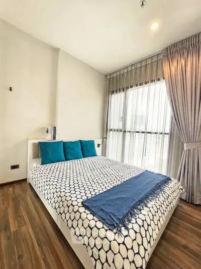 Modern bedroom with stylish decor and large window offering natural light.