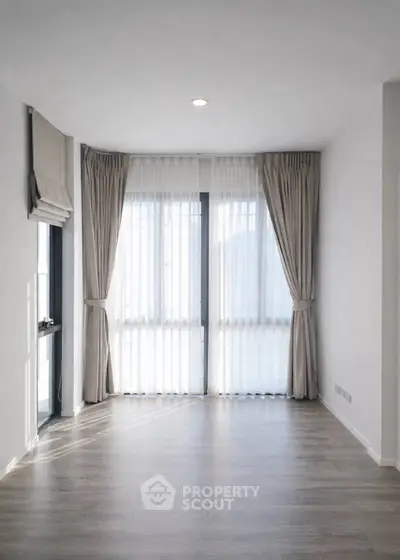 Spacious empty room with large windows and elegant curtains, perfect for customization.