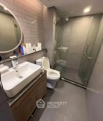Modern bathroom with glass shower and stylish vanity in sleek apartment.