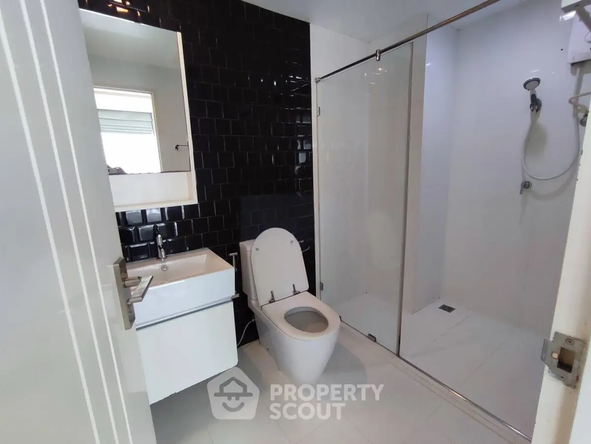 Modern bathroom with sleek black tiles and glass shower enclosure